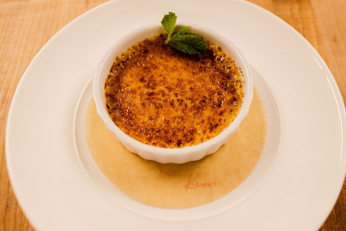 Crème brûlée on a paper liner stamped with the Kismet logo, seen from above