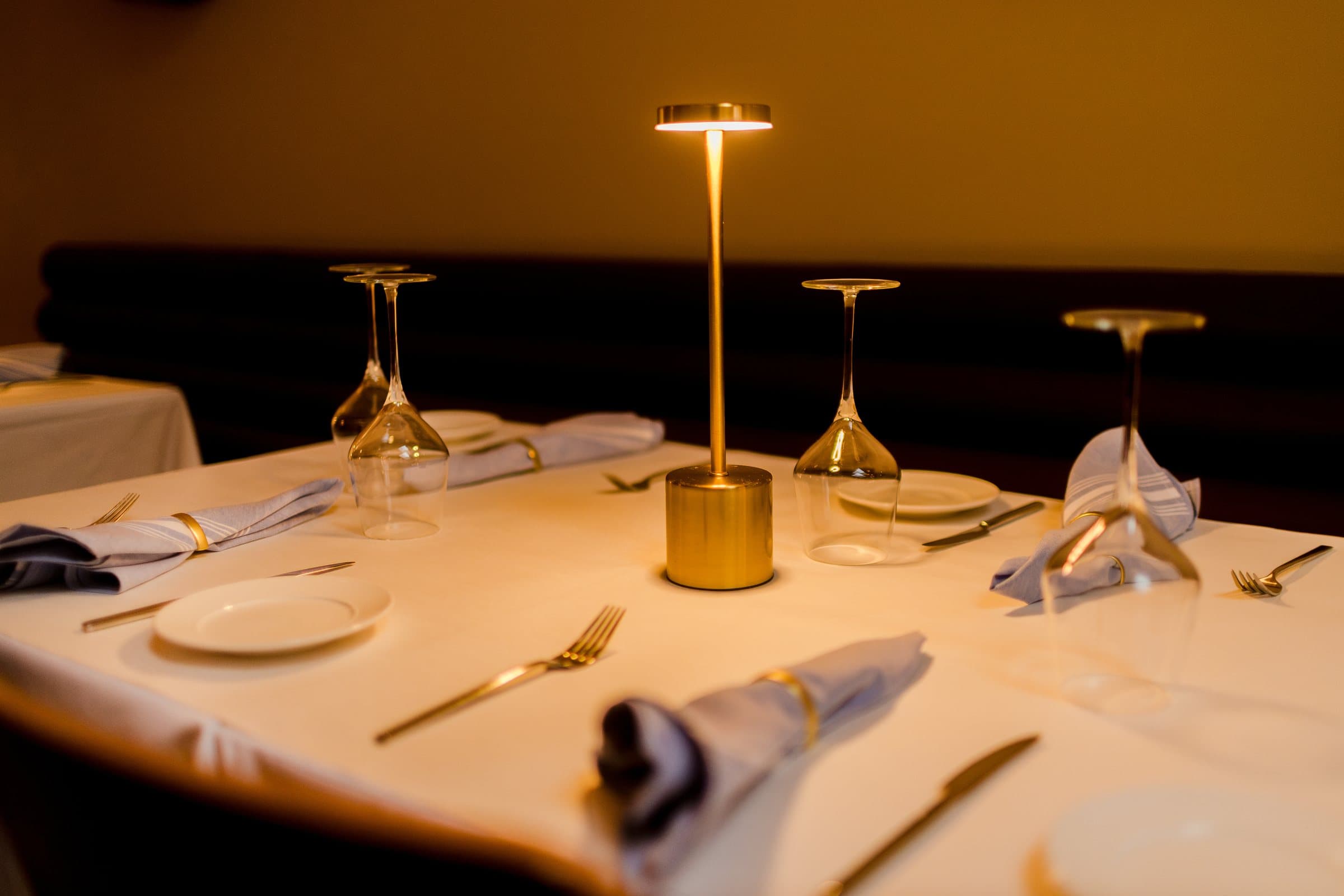 A brass table lamp glowing over a set table in the Kismet dining room